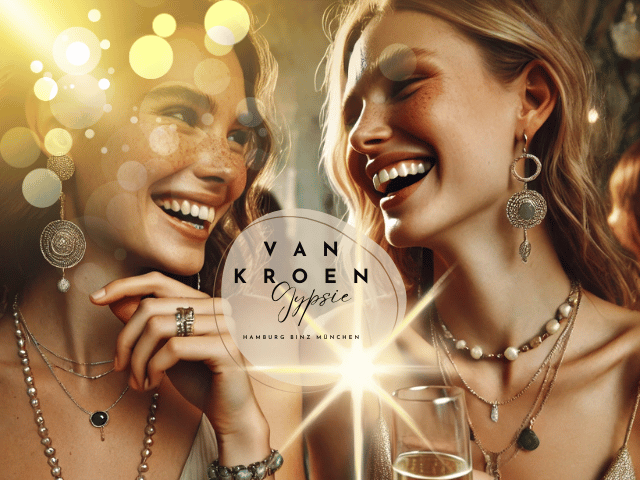 Zwei junge Frauen auf einer Gala, die sich unterhalten und ein Glas Sekt trinken. Beide tragen boho-inspirierte Modeschmuckstücke aus der Vanessa Van Kroen Kollektion, mit minimaler Schminke und natürlichen Sommersprossen. Die entspannte, elegante Atmosphäre wird durch sanfte Beleuchtung hervorgehoben und spiegelt eine freigeistige, elegante Stimmung wider."